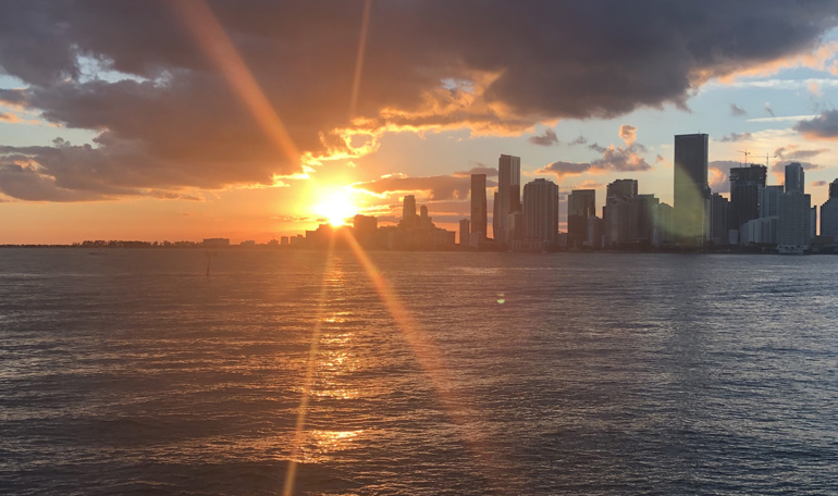 The sun sets behind the Miami skyline viewed from the Black Ice yacht.